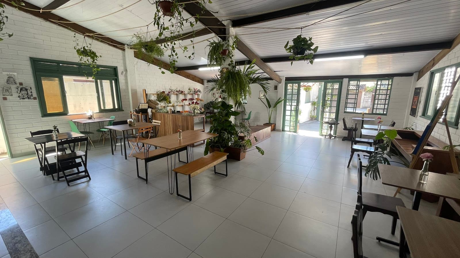 Salão da Alfazema — mesas comunitárias, plantas suspensas e o flower bar ao fundo